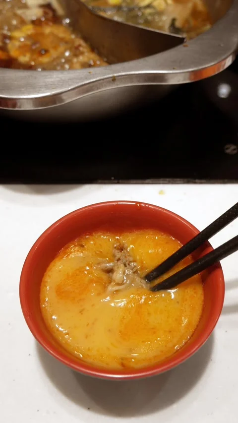 Using chopsticks dip meat in to raw egg hotpot shabu style. Stock Footage 306516535