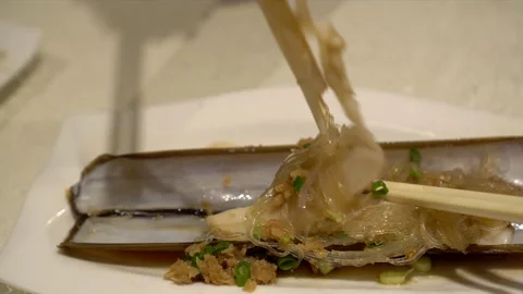 Using chopsticks to eat baked razor calm with glass noodle in Chinese food me Stock-Footage 197593728