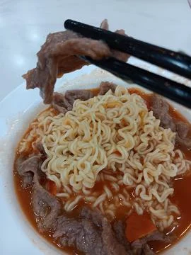 Using chopsticks to eat beef in tomato noodle soup Stock Photos