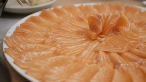 Using chopsticks pick a piece of fresh salmon sashimi in japanese restaurant Stock Footage 195320754