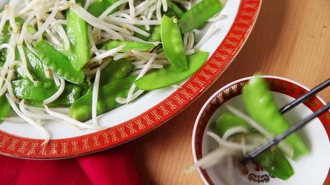Using chopsticks to serve snow peas and sprouts Stock Footage 102796000