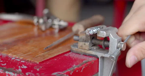 Using a clamp to firmly hold a bolt in place before filing the surface. Stock Footage 311665188