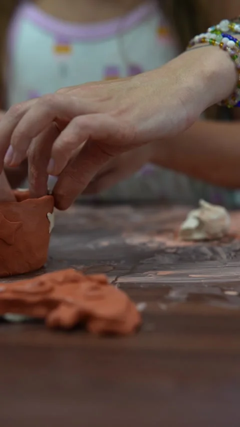 Using clay, the youngster is making figures on a wooden crafting table. Stock Footage 252094884