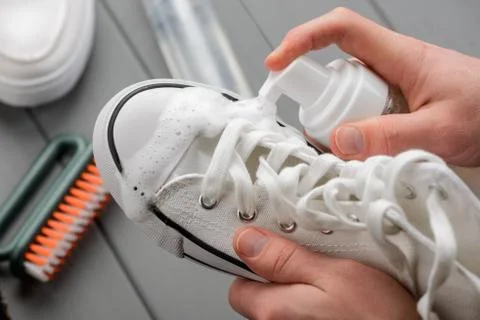 Using a cleaner spray to clear a white canvas sneaker Stock Photos