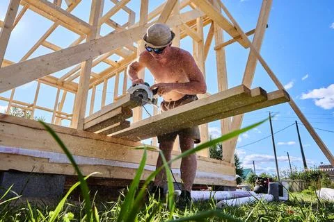 Using corded handheld circular saw with transverse motor to cut timber boar.. Stock Photos