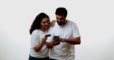 Using credit card, Indian couple smiles while shopping online with mobile Stock Footage 343164536