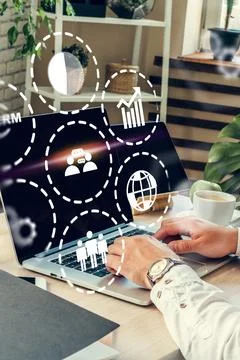 Using CRM software on a laptop in a modern office setting with charts and icons Stock Photos
