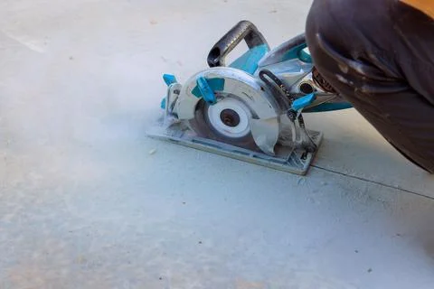Using cutting machine grinder, a construction worker cuts concrete foundations Foto stock