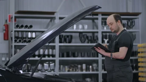 Using Digital Tablet For A Car Diagnostic. mechanic using a tablet pc at the Stock Footage 166078902