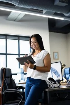 Using digital tablet, woman working in modern office with robotic hand model 写真素材