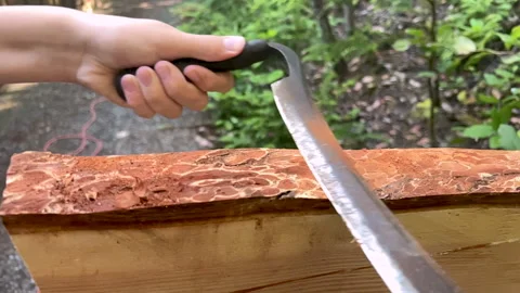Using a draw knife to remove bark from a wooden plank Stock Footage 283202435