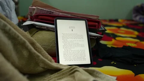 Using the ebook reader on the new ipad mini on top of a colorful bed sheet Stock Footage 167762937