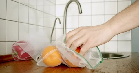 Using eco-tags. conscious consumption. close-up of a hand taking an orange Stock Footage 130519254