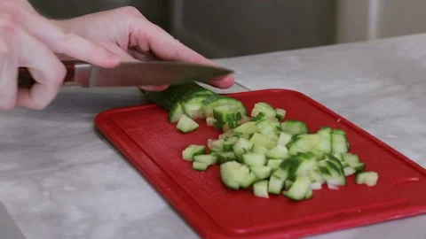 Using the edge of a knife, cut cucumber slices into cubes for salad Stock Footage 152467356