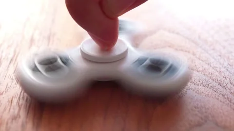 Using a fidget spinner on table in slow motion Stock Footage 130865449