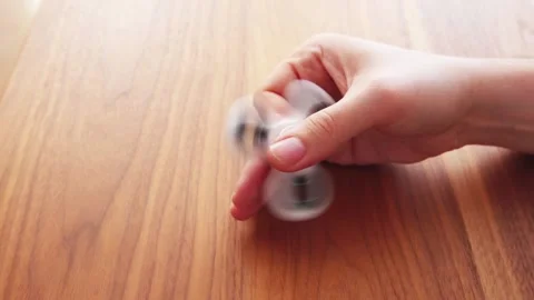 Using a fidget spinner on table in slow motion Vídeo Stock 130865475