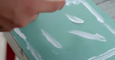 Using a finger to spread silicone glue evenly on the surface of the mirror. Stock Footage 312283580