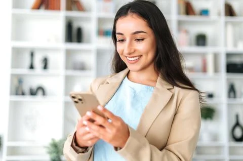 Using gadgets. Positive arabian or indian woman in a suit, stand in the office Stock-Fotos