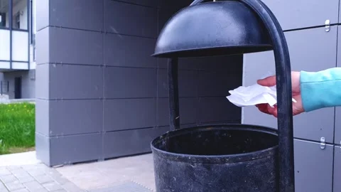 Using a garbage can, a woman throws  waste and paper into a metal garbage can. Stock Footage 310312827