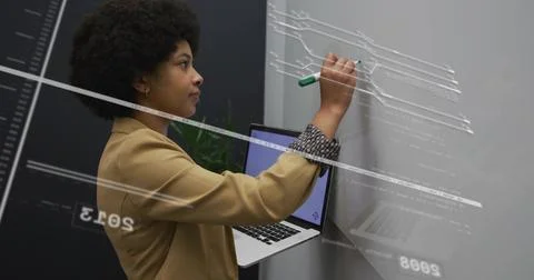 Using green marker on glass board developer holding laptop in office, with Stock Photos