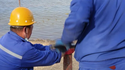 Using a hammer to hit wooden piles and install them, workers cooperate in the op Stock Footage 240199596