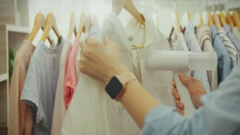 Using a hand-held iron steamer, a worker at a European boutique steams cloth Stock Footage 269235679