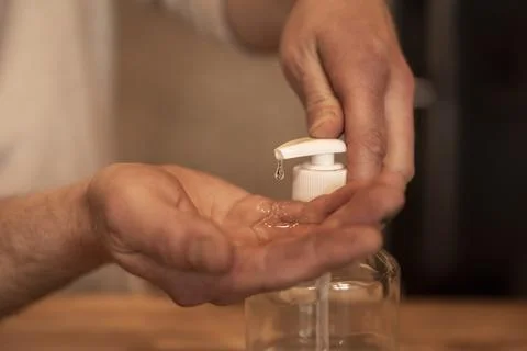 Using a hand sanitizer. Hands of a man using drops of disinfectant Stock-Fotos