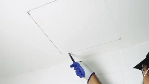 Using a handsaw cutting to cut a hole in the ceiling to install the service port Stock Footage 232215407