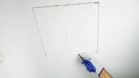 Using a handsaw cutting to cut a hole in the ceiling to install the service port Stock Footage 232215704