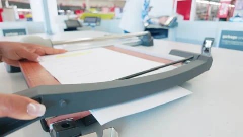 Using a heavy duty guillotine paper cutter on a office copy center counter Stock Footage 346660219