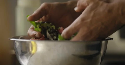 Using his hands the chef mixes the food in the stainless steel bowl in the .. Stock Footage 274655136