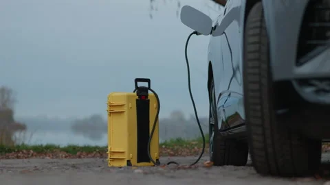 Using of home-invented portable battery to charge electric car out of the city Stock Footage 222889888