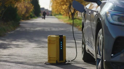 Using of home-invented portable battery to charge electric car out of the city Stock Footage 222890358