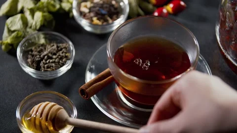 Using a honey dipper to add honey to the tea, cinnamon on the side, 4k Stock Footage 141572224