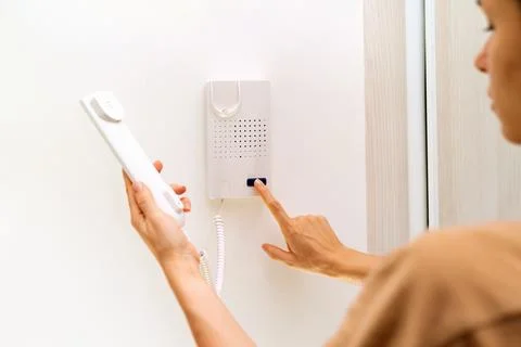 Using intercom at home. Woman uses intercommunication device at her apartment Stock Photos