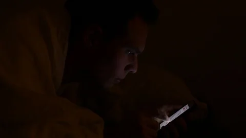 Using internet on smartphone in the bed under blanket by night Stock Footage 98100772
