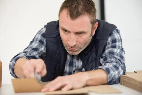 Using a knife to assemble a cardbox Stock Photos