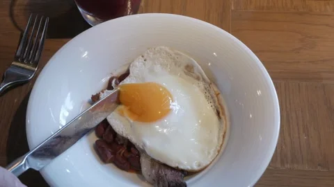 Using knife to break egg york in fried egg in a bowl of fried grilled pork .. Stock Footage 271616640