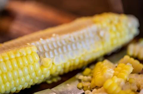 Using a knife to remove kernels from the cob of an ear of sweet corn. Foto stock