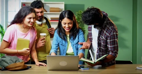 Using laptop, college students stand and study together with notes in library Stock Footage 342383322