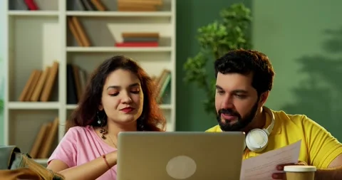 Using laptop to complete assignment Indian students studying together in library Vídeo Stock 342383126