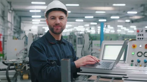 Using the laptop. Factory worker is indoors with hard hat. 動画素材 297477291