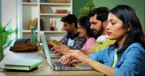 Using laptop, Indian students focus on group study with books notes in library Vídeo Stock 342383435