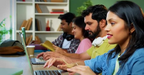 Using laptop, Indian students focus on group study with books notes in library Vídeo Stock 342383439