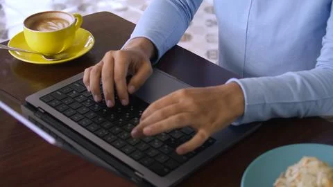 Using a laptop at table with coffee. Typing with fingers Stock Photos