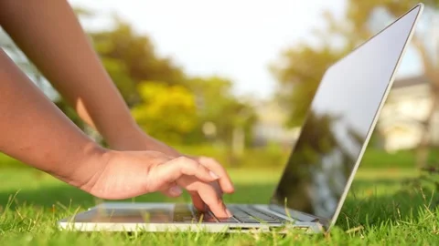 Using a laptop in a vibrant park with green space. Video stock 316141389