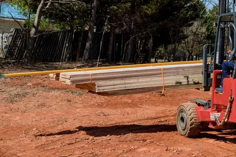 Using a lift manipulator, a construction site worker unloads a delivery of Stock Photos