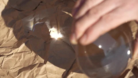 Using magnifying glass and sunlight, burning occurs on paper surface, closeup Stock Footage 304786291