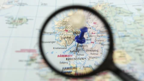 Using a magnifying glass to explore a paper map of Aalborg Stock Footage 340078878