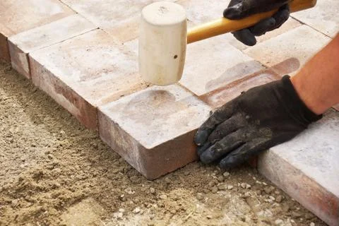 Using a mallet to set paver Stock Photos
